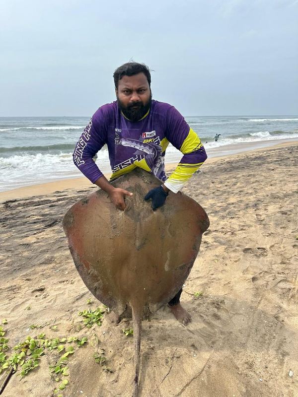 Customer with a large stingray on the beach before release